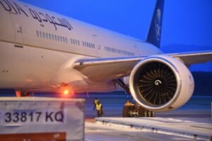A commercial jet parked on the tarmac at Geneva Airport during twilight.