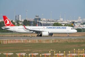 Turkish Airlines Airbus A321neo on the runway at Manises airport, ready for takeoff with a clear, sunny sky.